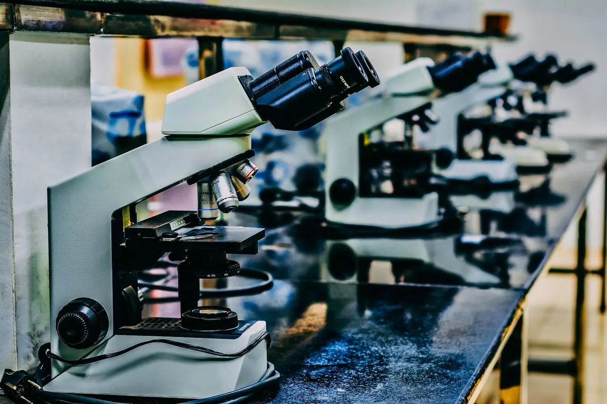 A white microscope on a dark table.