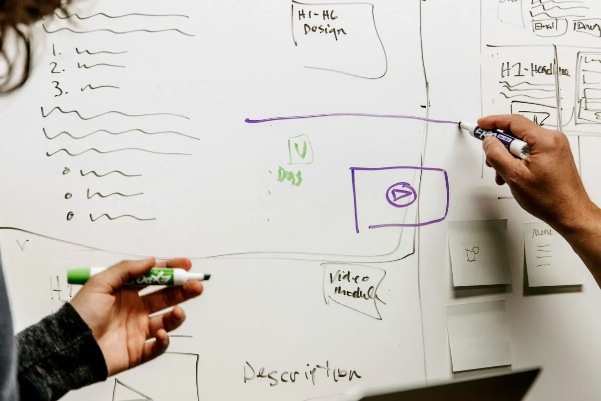 Two people drawing on a whiteboard together.