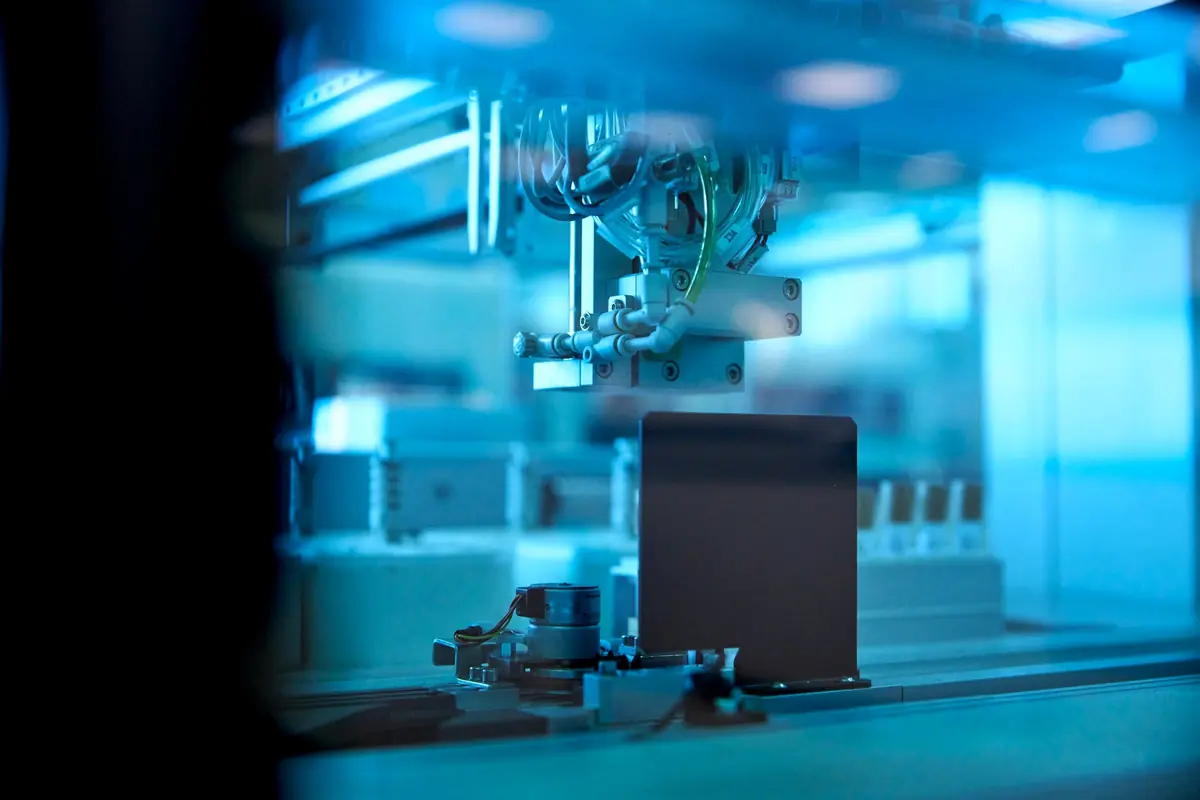 An industrial robotic arm in a blue-lit factory.